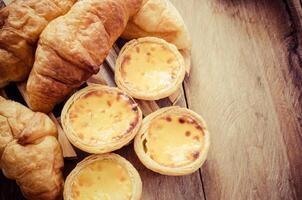 huevo tartas y croissants en un de madera mesa - tono Clásico foto