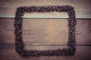 Rectangle frame made of coffee beans on the wooden background photo