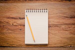 blank notebook with pencil on wooden table photo