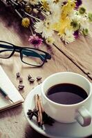 Coffee mugs and eyeglasses placed flowers on the wooden floor in the morning. photo