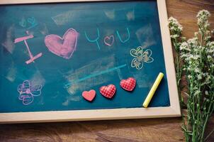 Blackboard with words written in shock that the I LOVE YOU and a floral heart was placed next to the board - the concept of Valentine's Day. photo