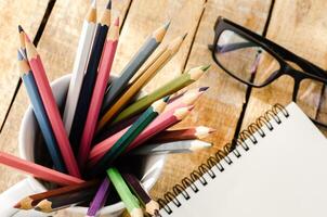 Notebooks, pencils, Equipment on the wooden floor with the morning sun shining faintly. photo