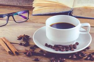 libro lente y taza de café en madera a Mañana foto