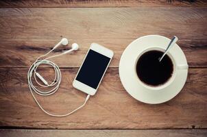 top view image of smartphone with blank screen headphones coffee cup and costome on wooden floor photo