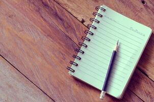 blank notebook with pencil on wooden table - still life photo