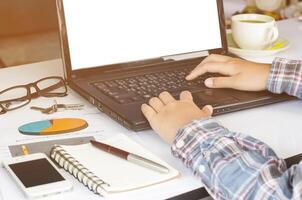 Businessman at work. Close-up top view of man working on laptop and data  while sitting at the wooden desk photo