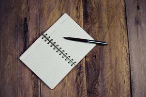 blank notebook with pen on wooden table - still life photo