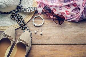 accessories for teenage girl on her vacation, hat, stylish for summer sunglasses, shoes and costume on wooden floor. photo