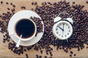 Coffee and coffee beans are placed near the alarm clock - concept articles useful as well photo