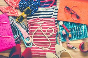 Colorful clothes and accessories to dress arranged on a wooden table. photo