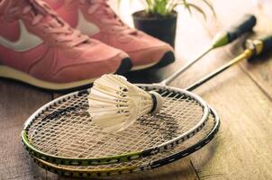 Shuttlecock and badminton racket with sport shoes on wooden floor for exercise photo