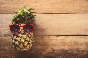 Pineapple sunglasses resting on the wooden floor concept travel. photo