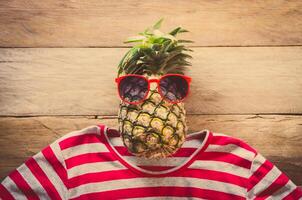 Pineapple sunglasses resting on the wooden floor concept travel. photo