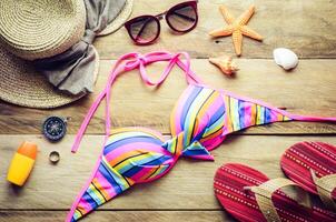 Beauty colorful bikini and accessories on wooden floor for trip on summer photo