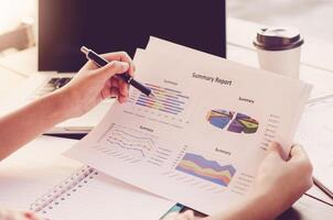 Businessman holding paperwork on the table and analyzing investment chart working in office. Business work concept photo