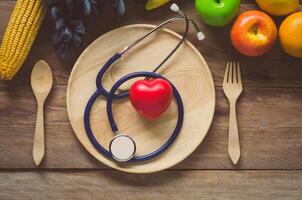 Healthy concept, fruit and ear doctor on wood background photo