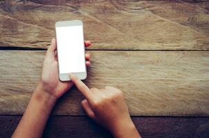 Hand holding smart phone isolated on wooden background photo