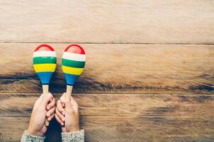 Hand holding Maracas on wooden floor. photo