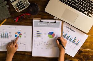 Businessman holding paperwork on the table and analyzing investment chart working in office. Business work concept. photo