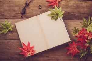 Maple leaf on wooden background at summer and notebook for your text photo