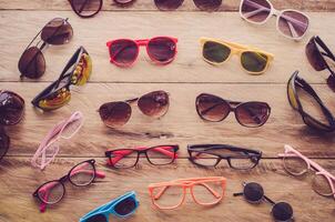 Many sunglasses fashion and eyeglasses on the wood photo
