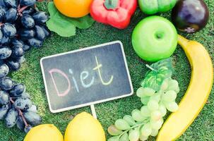 The concept of diet for weight loss - Exercise Equipment and word   diet  in wooden place on the green grass photo