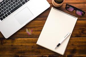 White notebooks and laptop laying on a wooden table photo