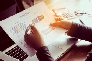 Businessman holding paperwork on the table and analyzing investment chart working in office. Business work concept. photo