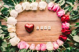 vistoso rosas forrado arriba en un de madera piso con corazón y palabra amor concepto para amor foto