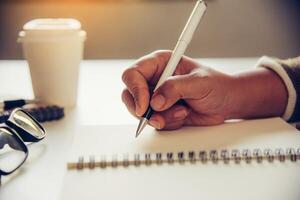 The woman's hands are writing note and coffee cup in open spect and light gold in morning photo