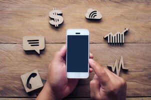 Handheld mobile and business icons placed on wooden floor - Concept of doing business online. photo