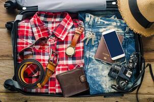 Clothing traveler's Passport, wallet, glasses, smart phone devices, on a wooden floor in the luggage ready to travel. photo