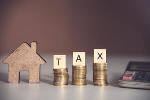 Tax concept blocks word  TAX on coin stack and calculator on wooden floor photo