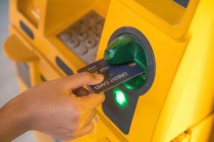 mano insertando con un crédito tarjeta dentro banco máquina . hombre utilizando un Cajero automático máquina con crédito tarjeta a retirar dinero foto