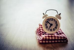 White alarm clock and handkerchief on white table photo