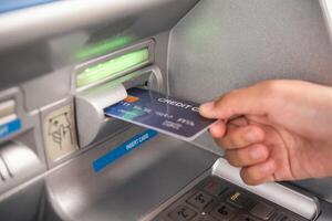 Hand inserting with a credit card into bank machine . Man using an atm machine with  credit card to withdraw money photo