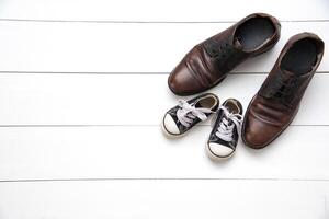 The shoes of father and son on wood white background - concept take care photo