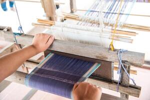 The hand of a weaver is woven with a hand-woven machine. photo