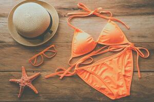 Beauty orange bikini and accessories on wooden floor for trip on summer photo