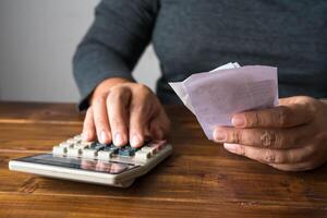 Hand on calculator to calculate cost based on holding bill. photo