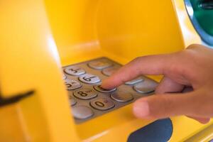 mano insertando con un crédito tarjeta dentro banco máquina . hombre utilizando un Cajero automático máquina con crédito tarjeta a retirar dinero foto