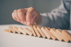 Businessman hand stopping the domino wooden effect concept for business. photo