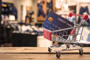Small shopping cart with credit card inside and behind is blurred. Shop - concept use credit for shopping. photo
