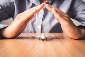 mano proteger el icono un avión - el concepto de seguro para viaje foto