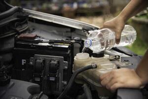 Professional mechanic checking filling water to car radiator. concept for safety before travel photo