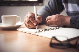 The hand of a man holding a pen and taking notes in a notebook. photo