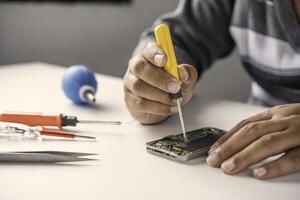 Repairman disassembling Repairman disassembling smartphone with screwdriver. photo