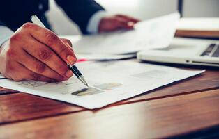 Business people are working on accounts in business analysis with graphs and documentation. photo