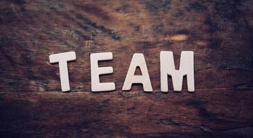 The word TEAM is arranged from a wooden letter placed on a wooden floor. photo