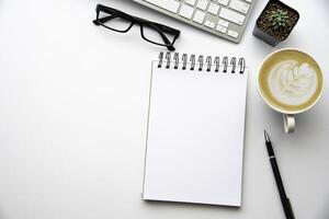 Top view with copy space, working desk with laptop,cell phone,notebook pencil and coffee on white background photo